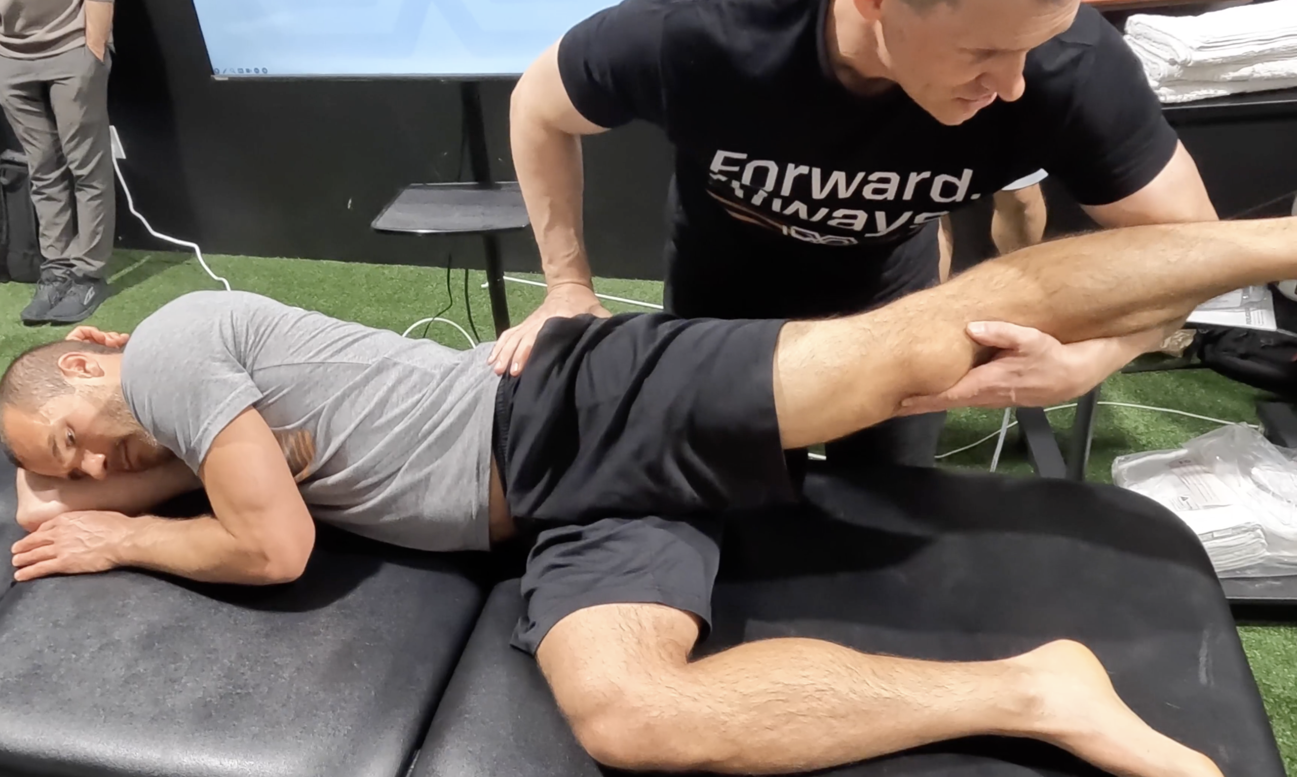 Kineziolog izvaja test gibljivosti kolka in pri tem stabilizira medenico za natančnejšo meritev